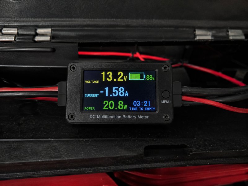DC battery monitor LCD showing 13.2V voltage, current draw, power watts, and battery percentage inside toolbox