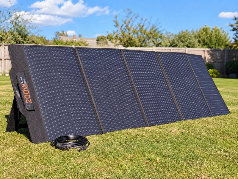 200W foldable briefcase-style solar panel deployed on grass with kickstand and MC4 cables