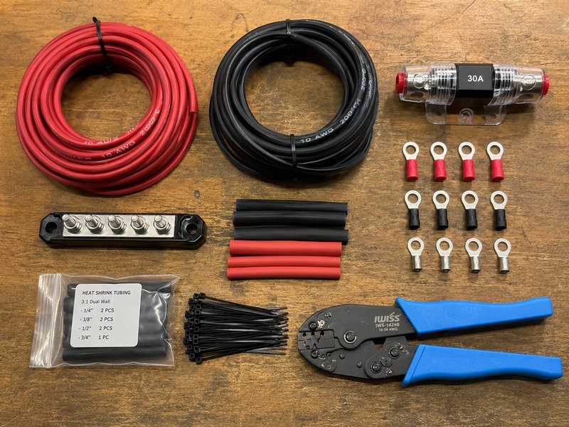 Flat lay of 10 AWG wire, 30A inline fuse, bus bar, ring terminals, heat shrink, zip ties, and crimping tool